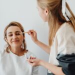 Kobieta wykonuje delikatny makijaż dzienny innej kobiecie w salonie