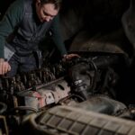 Mechanik pochylony nad silnikiem diesla w warsztacie