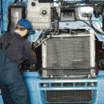Mechanik w kombinezonie sprawdza silnik ciężarówki w warsztacie