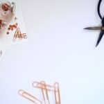 Minimalistyczne biurko z nożyczkami, spinaczami i zdjęciami na białym blacie