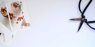 Minimalistyczne biurko z nożyczkami, spinaczami i zdjęciami na białym blacie
