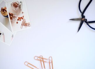 Minimalistyczne biurko z nożyczkami, spinaczami i zdjęciami na białym blacie