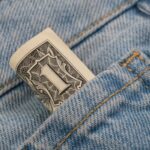 Zwinięty banknot dolarowy w kieszeni dżinsów, symbol oszczędzania