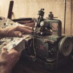 Ręce szyjące na starej maszynie w słabo oświetlonej pracowni