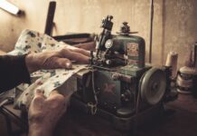 Dlaczego dawniej ubrania dziedziczono, a nie wyrzucano i co z tego może wziąć współczesny krawiec Ręce szyjące na starej maszynie w słabo oświetlonej pracowni