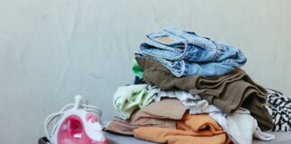 Jak prasować różne tkaniny, żeby ich nie spalić i poprawić wygląd każdego szwu Stos świeżo wyprasowanych ubrań obok żelazka parowego na desce